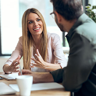 a lady and business man talking in a 1-1 businessn coaching session