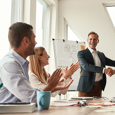 a leadership coaching session with a clipboard in the background and people clapping and smiling